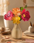 Illustrative lifestyle image of a completed colorful paper flower bouquet in a folded paper vase