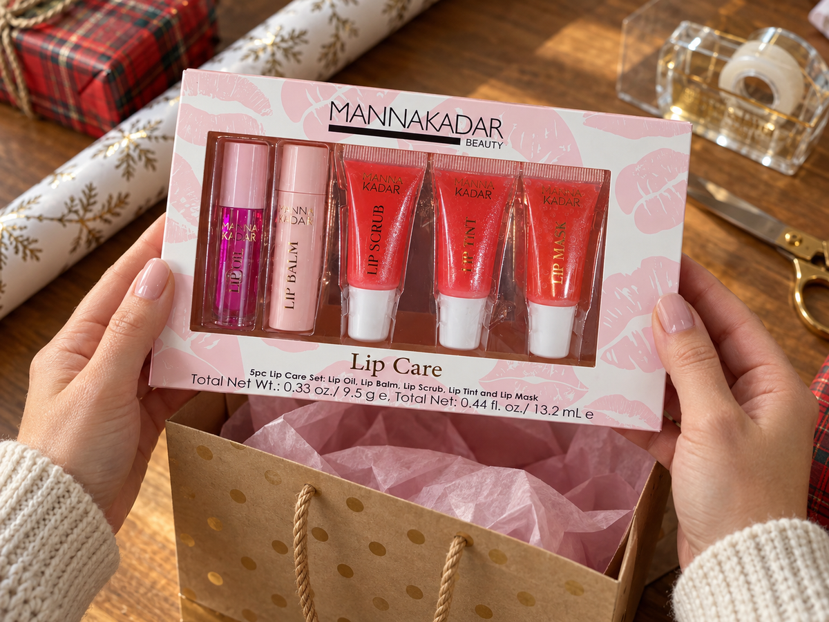 Hands placing the boxed Manna Kadar five-piece Lip Care Set into a gift bag.