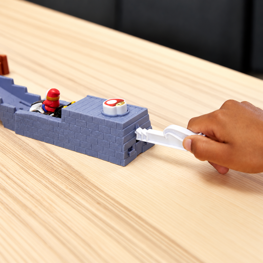 Hand pulling back the mushroom launcher with the included Shy Guy kart ready on the track