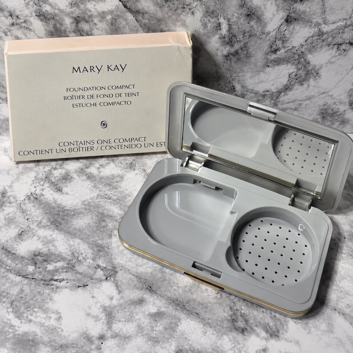 Mary Kay Foundation Compact 869100 with empty D-shaped refill well, mirror and sponge compartment beside its box