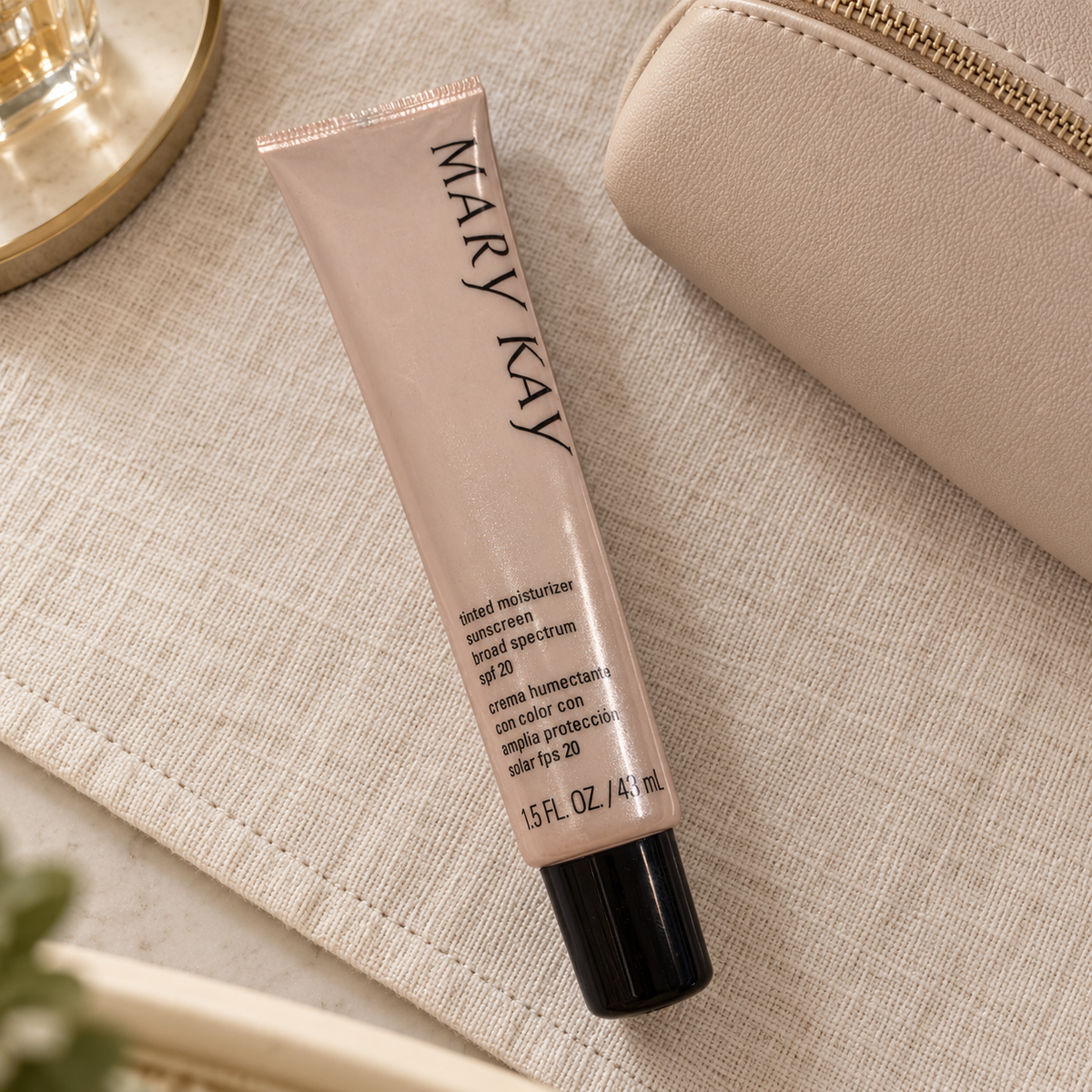 Mary Kay Beige 2 tinted moisturizer tube beside a closed cosmetic pouch