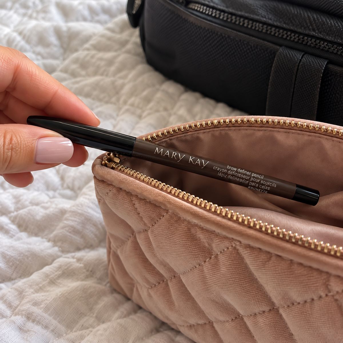 A capped Mary Kay Brunette Brow Definer Pencil being placed in a makeup pouch.