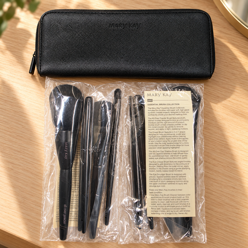 Mary Kay Essential Brush Collection in protective sleeves with black zippered case and product guide on an oak dressing table