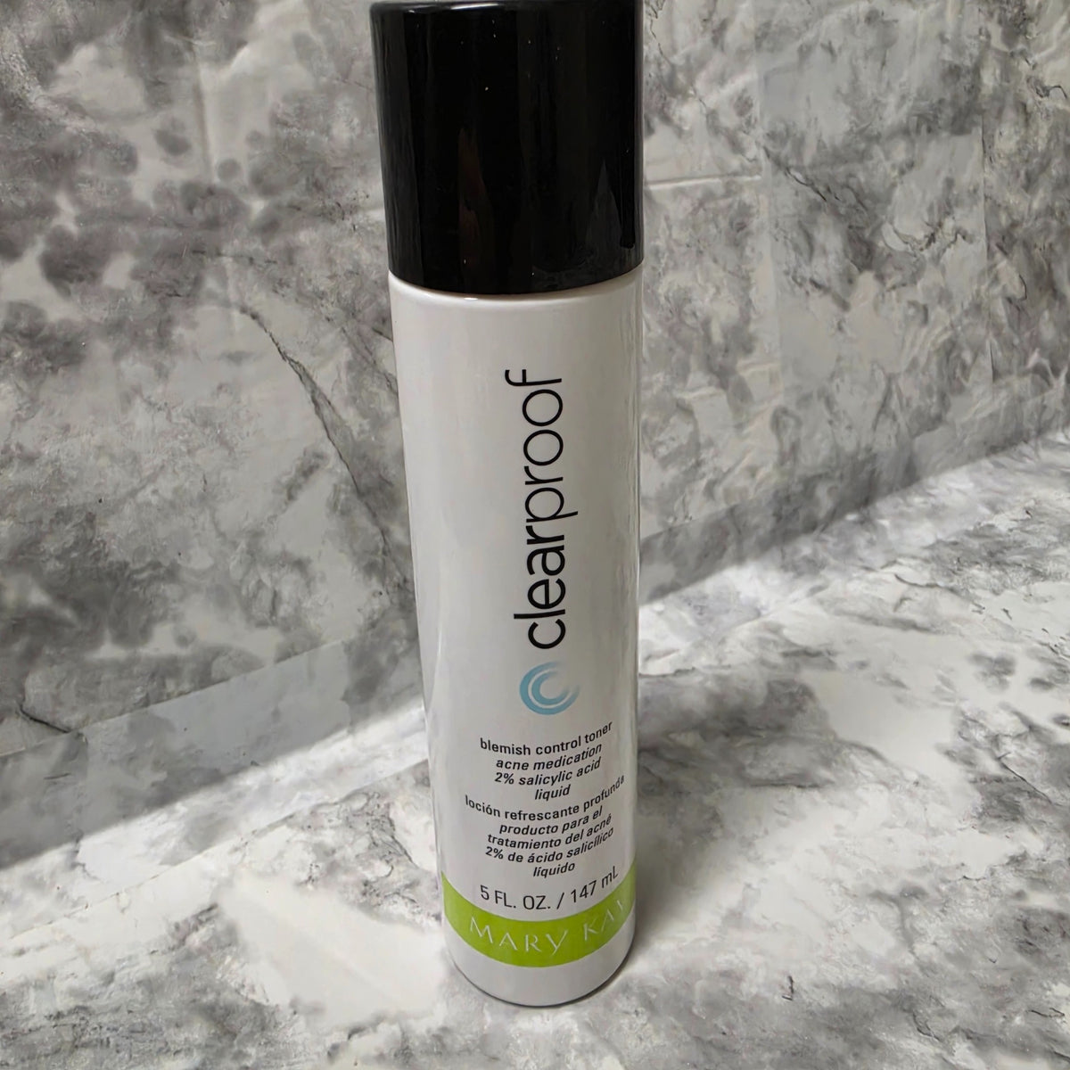 Mary Kay Clear Proof Blemish Control Toner 5 fl oz bottle with black cap on a gray marble background