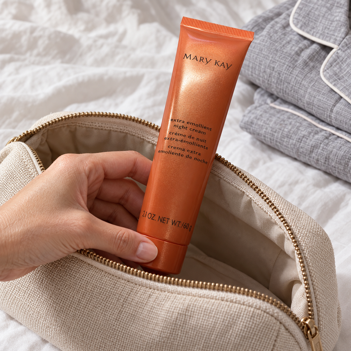Mary Kay Extra Emollient Night Cream orange tube being placed into an overnight toiletry pouch