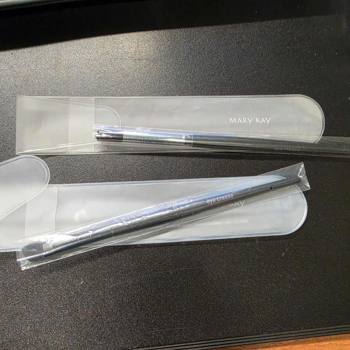 Actual Mary Kay Eye Crease Brushes in clear protective pouches, showing chrome and black ferrule variations