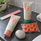 Mary Kay foot-care bundle on a slate bathroom counter with nail file, two orange toe separators and sealed gray pumice stone