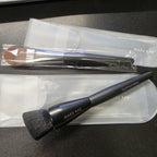 Actual new Mary Kay liquid foundation brushes in protective pouches, showing flat paddle and angled buffing styles