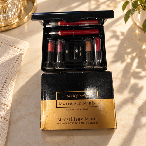Mary Kay Marvelous Minis lipstick set and black-and-gold box on an ivory dressing table in warm window light