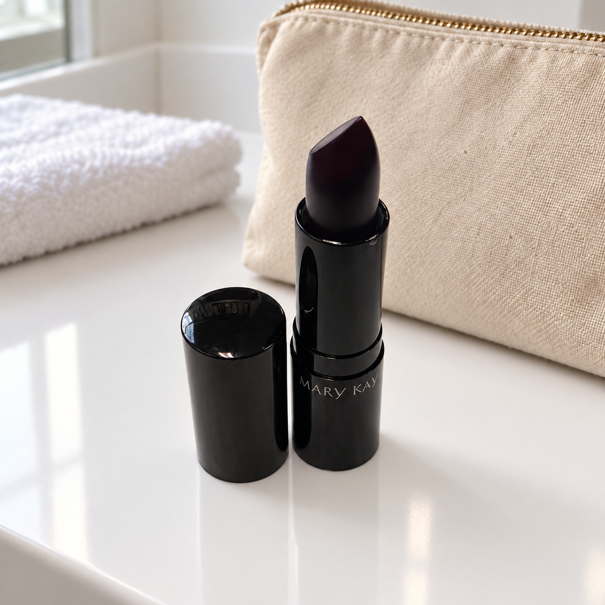 Mary Kay Puro Mirtillo matte lipstick and cap beside a beige travel pouch