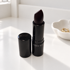 Mary Kay Puro Mirtillo matte lipstick on a white vanity beside a jewelry dish