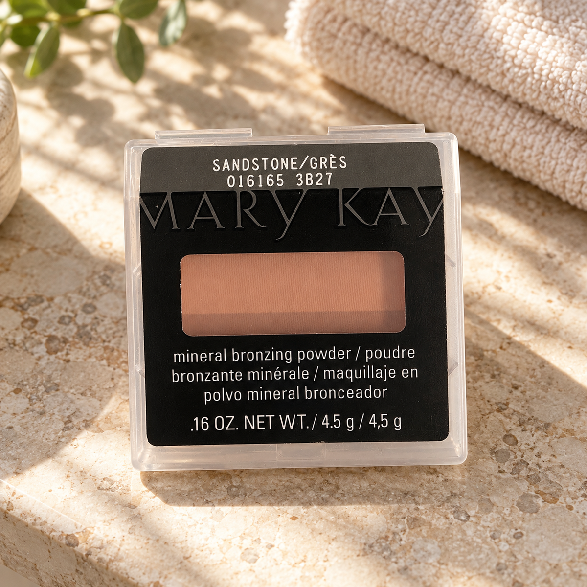 Mary Kay Sandstone mineral bronzing powder on a stone vanity beside a folded towel