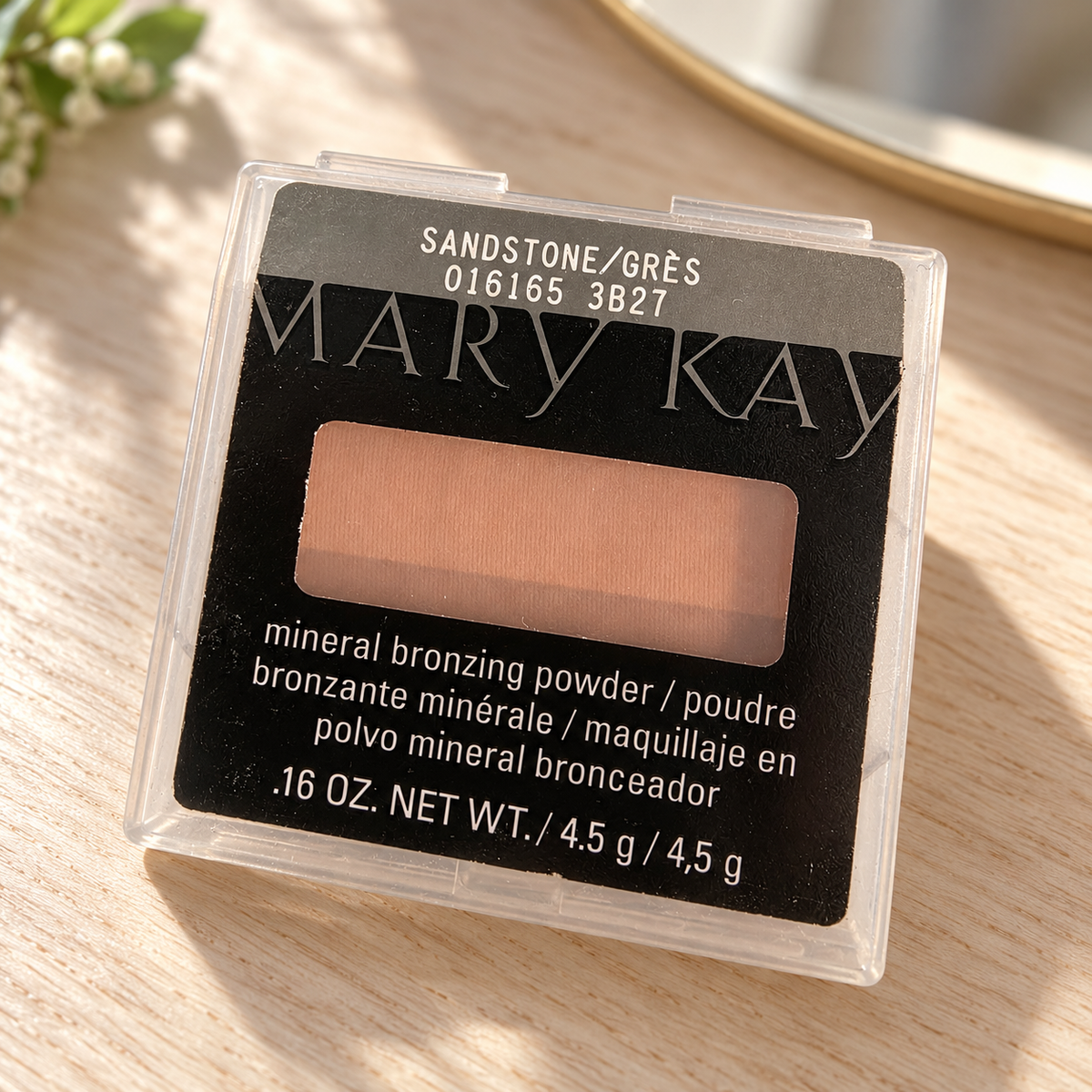 Mary Kay Sandstone mineral bronzing powder in its clear package on a pale wood vanity