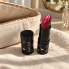 Mary Kay Empower Sparkle Cream Lipstick beside a beige makeup pouch on linen