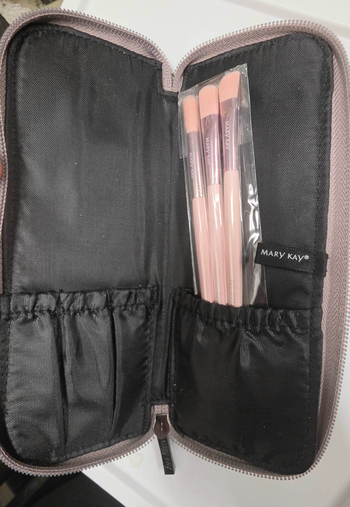 Mary Kay three pink eye brushes in protective sleeves inside the open metallic zippered case