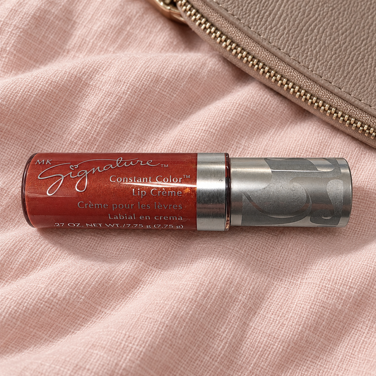 Mary Kay Tropical Spice Lip Crème beside a taupe makeup pouch