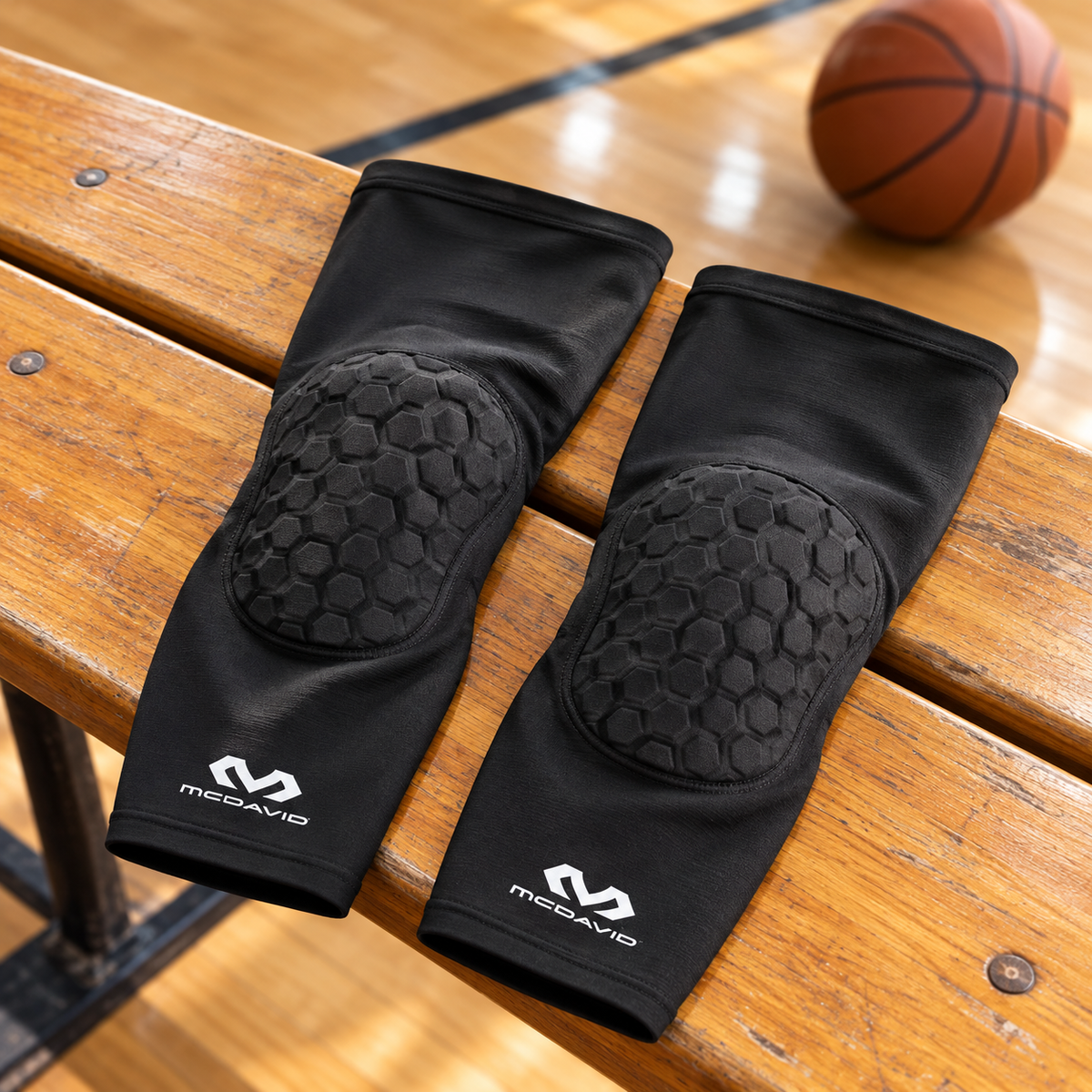 AI-generated illustration of a black pair of McDavid 6446 HEX extended leg sleeves laid on a wooden gym bench.