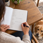 Pet owner writing contact details in the blue Mead pet planner at home