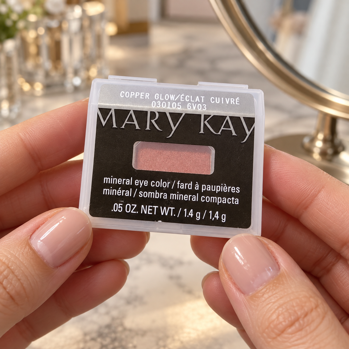 Holding the closed Copper Glow Mineral Eye Color refill case at a dressing table
