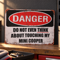 MINI COOPER novelty metal sign resting on a garage shelf, with distressed red, black and off-white lettering.