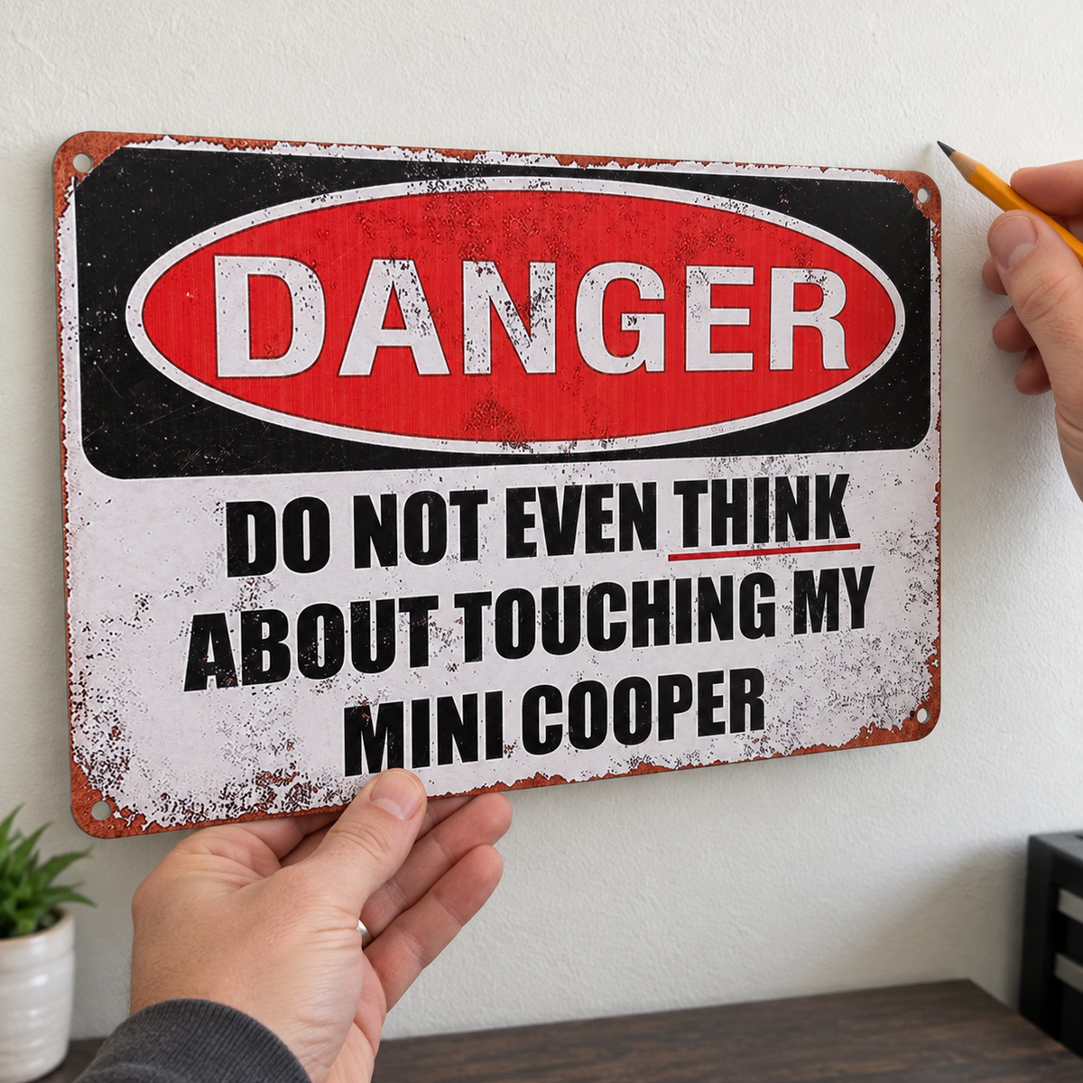 MINI COOPER novelty metal sign held against a wall while planning its placement with a pencil.