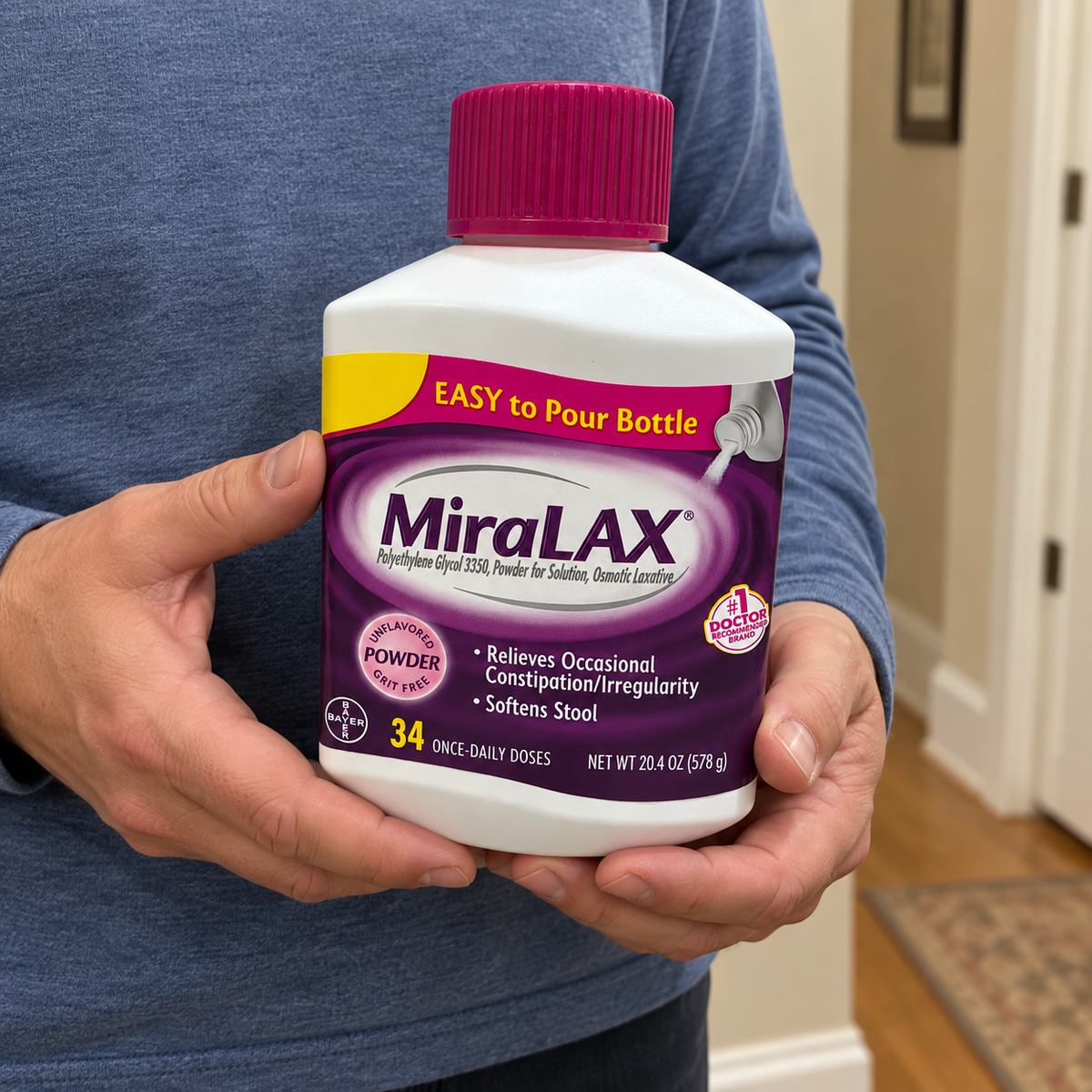 Holding a capped MiraLAX 20.4 oz. bottle with both hands