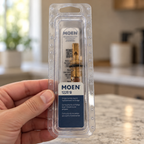 Adult hand holding the clear package of a Moen 1225B replacement cartridge.