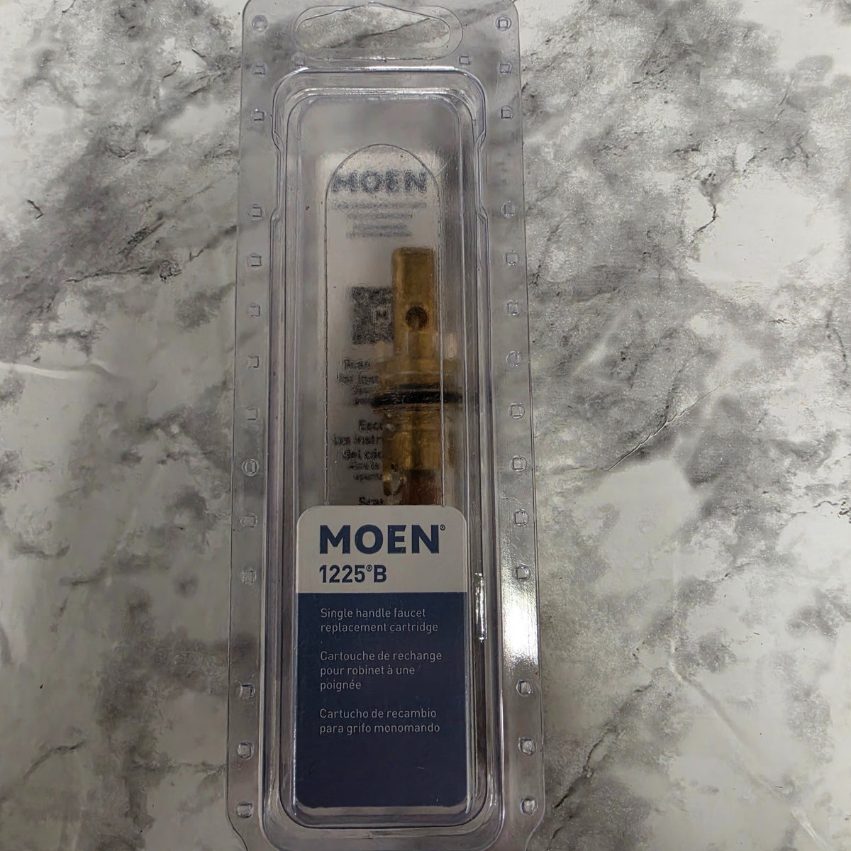 Moen 1225B single-handle faucet replacement cartridge in its original clear package on a marble-patterned surface.