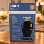 Moen Host EX75c 3/4 HP retail carton in a warm evening kitchen setting; package illustration shows the black corded disposal.