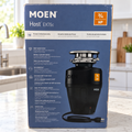 Moen Host EX75c 3/4 HP retail carton in a bright kitchen countertop setting; package illustration shows the black corded disposal.