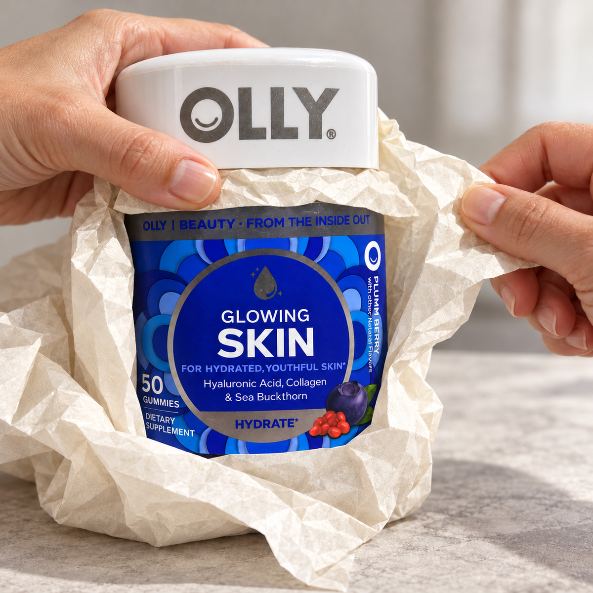 Hands unwrapping an OLLY Glowing Skin gummy jar.