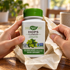 AI-generated illustration. Adult hands unwrap a closed Nature’s Way Hops Flowers 100-vegan-capsule bottle from plain paper. Paper is a scene prop.