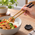 AI-generated illustration of an adult lifting a bite with one black-ended Infuse Spring Day chopstick pair; food and bowl are scene props.