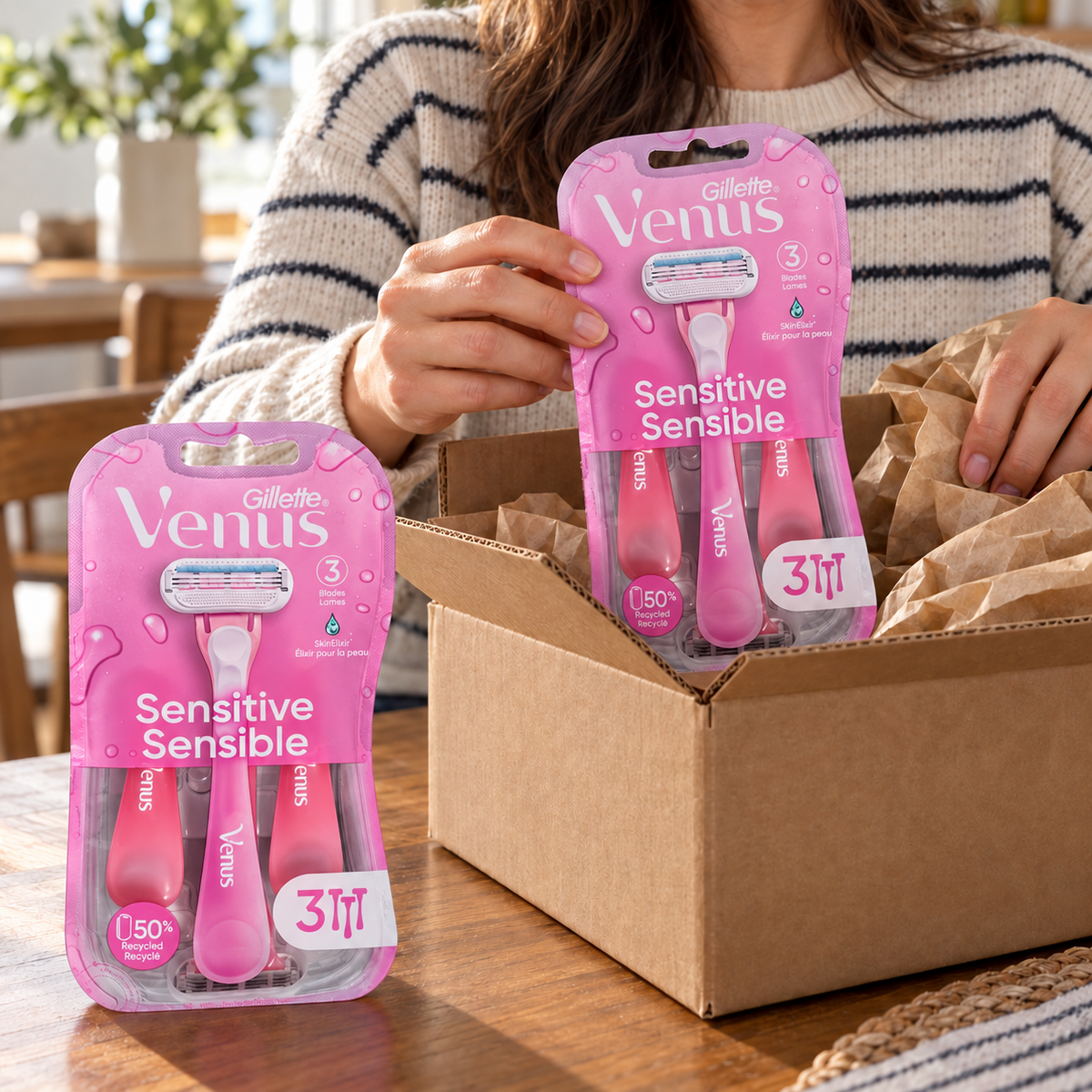 An adult unpacks two pink Gillette Venus Sensitive three-count razor packs from a shipping box, six razors total.