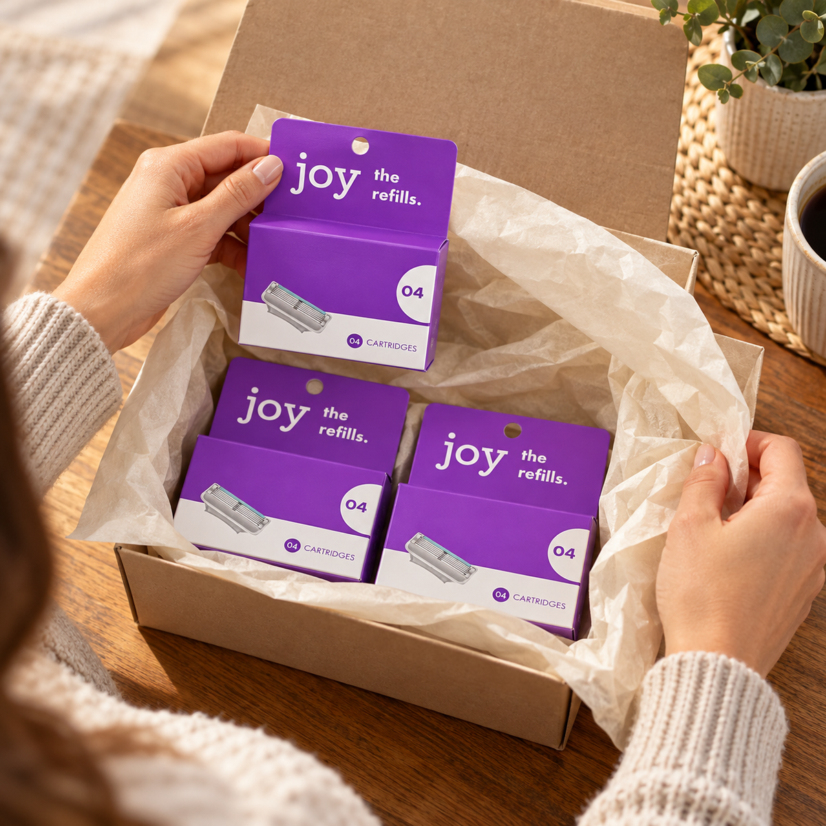 Adult hands reveal three purple joy four-cartridge refill cartons in a gift box, twelve cartridges total.