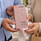 Adults exchanging a KEVIN.MURPHY ANGEL.RINSE 250 mL conditioner bottle in tissue wrapping
