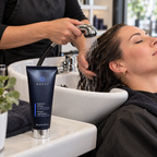 Hair being rinsed at a salon basin with the MONAT Replenish Masque 60 mL tube beside it