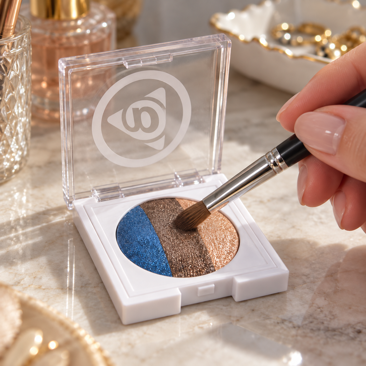 A brush picking up the brown shade from an open Out of the Blue eye trio