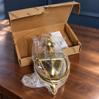 AI-generated context: the bagged Baldwin Colonial brass knocker and opened box on a walnut console; console is not included.
