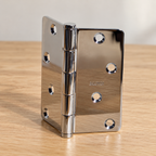 AI-generated product detail: one Baldwin polished-chrome hinge partly open on a wood surface.