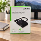 AI-generated lifestyle illustration of the Belkin AVC001 VGA + Charge Adapter retail box in a home office; background props not included
