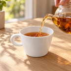 Tea pours from a glass teapot into a smooth white Bernardaud Organza Opus teacup.
