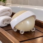 Mary Kay body massager on a wooden bath tray beside rolled washcloths