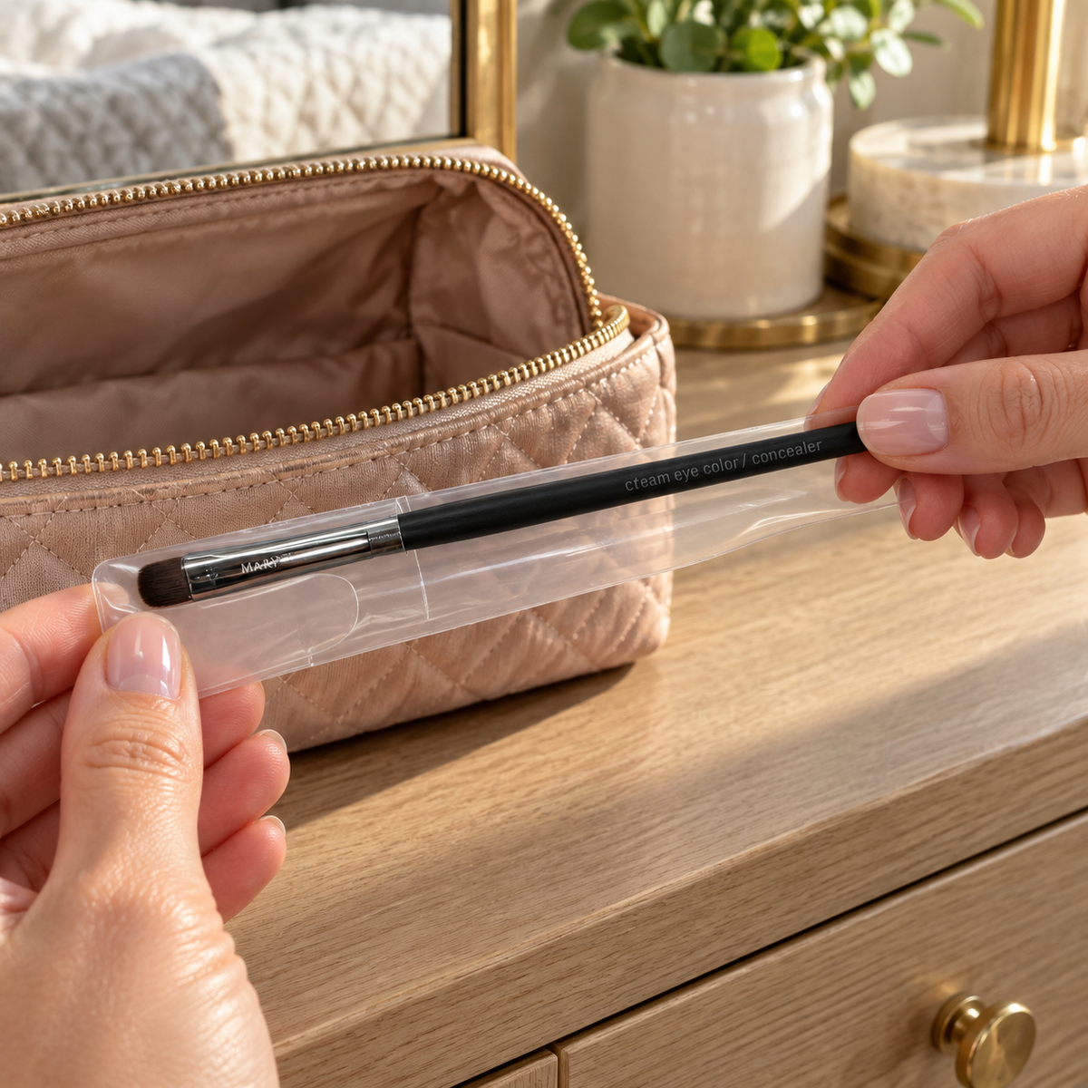 Placing the Mary Kay cream eye color and concealer brush into its clear sleeve beside a makeup bag.
