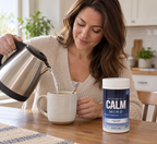 Pouring warm water into a mug beside Natural Vitality CALM Mind unflavored drink mix.