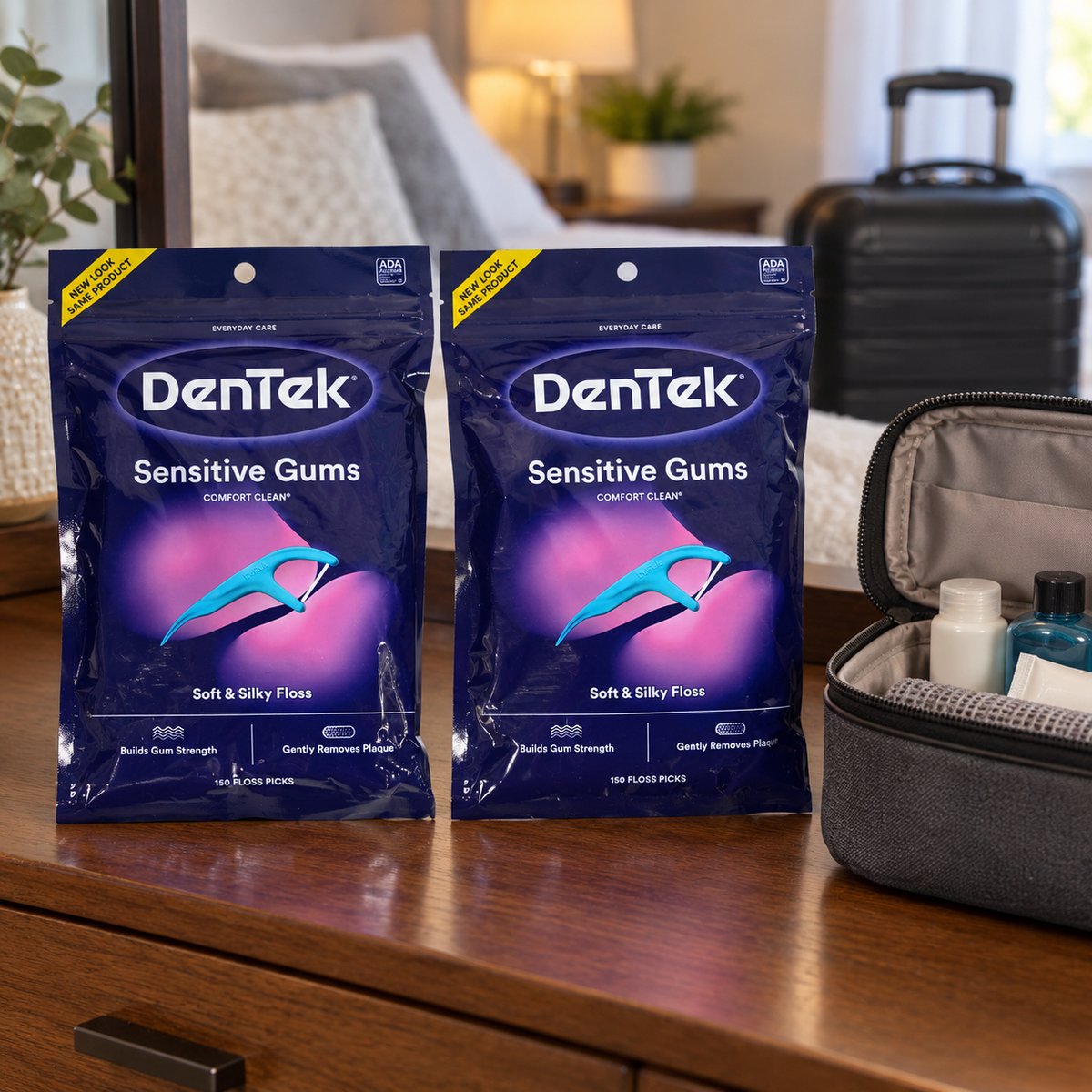 AI-generated lifestyle illustration of exactly two DenTek Sensitive Gums Comfort Clean 150-count bags on a dresser beside a toiletry case and carry-on bag; setting props are not included.