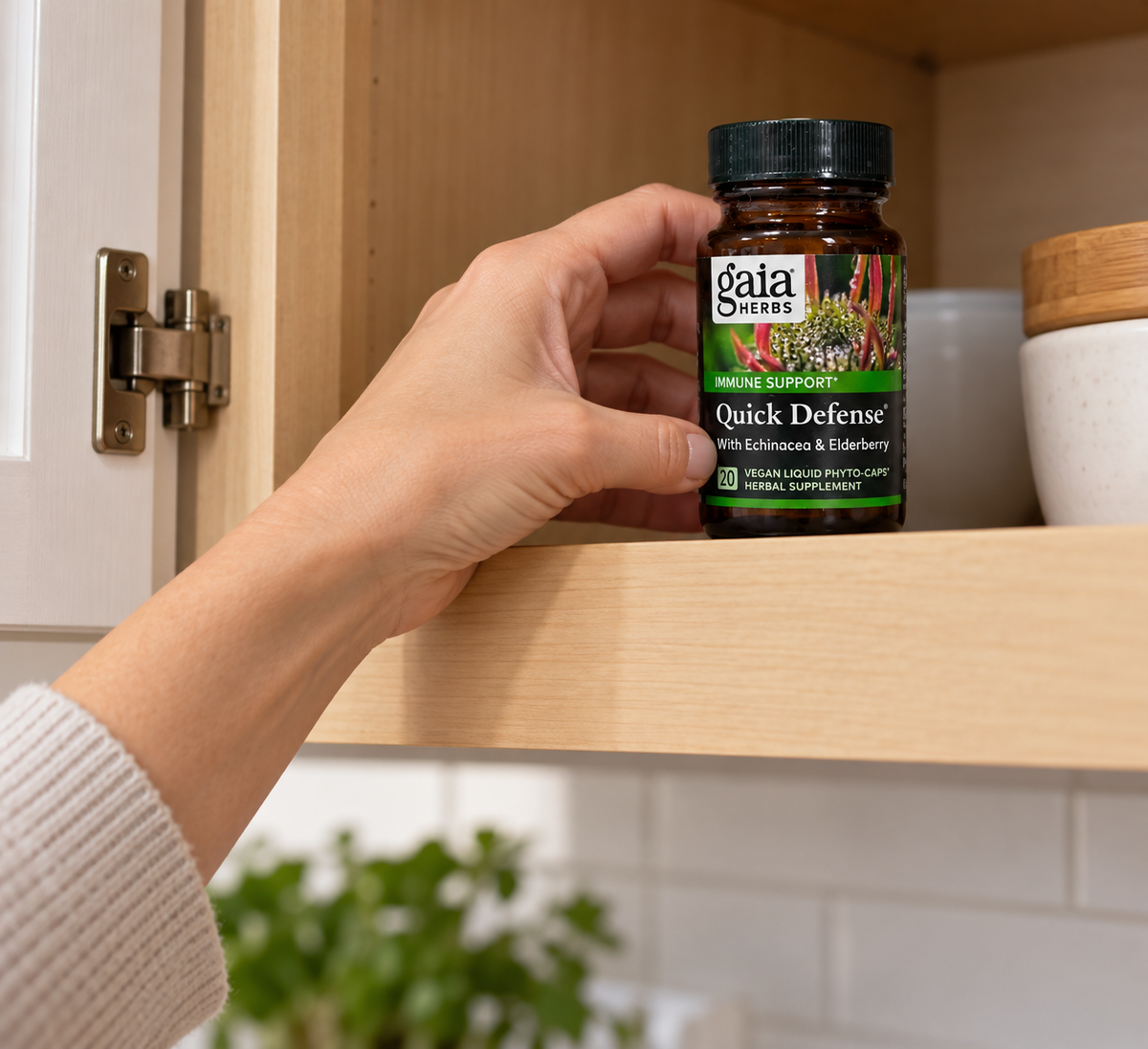 Returning a closed Gaia Herbs Quick Defense 20-capsule bottle to a cupboard.