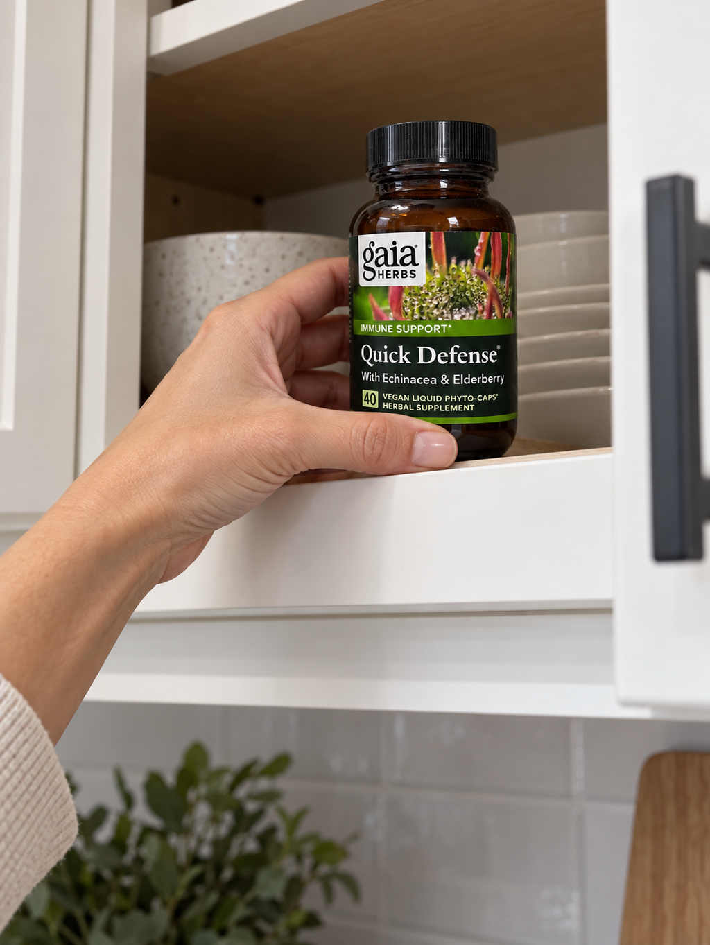 Placing a closed Gaia Herbs Quick Defense 40-capsule bottle in a cupboard.