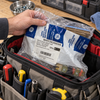 A sealed GE WH13X26534 water inlet valve package being packed in a technician tool bag