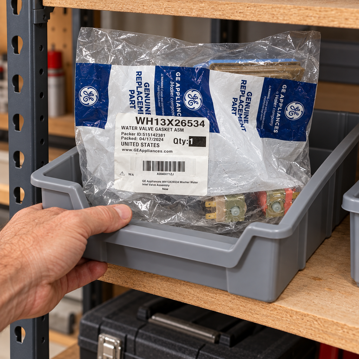 A sealed GE WH13X26534 valve package stored in a dry workshop parts bin